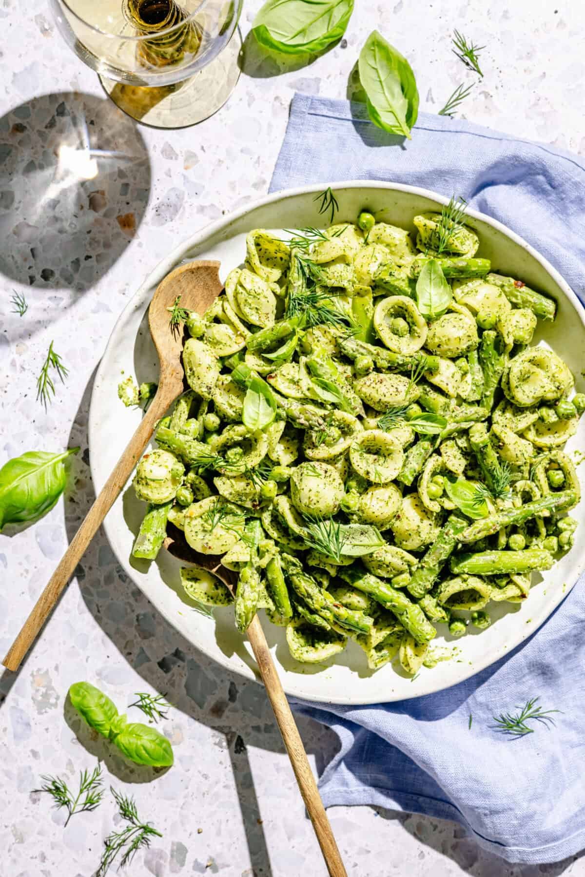 Green Goddess Pasta Salad in white serving bowl with two serving spoons.